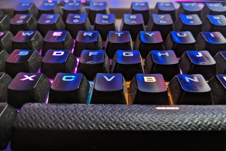 A close-up of a dirty, backlit keyboard with visible wear on some keys.